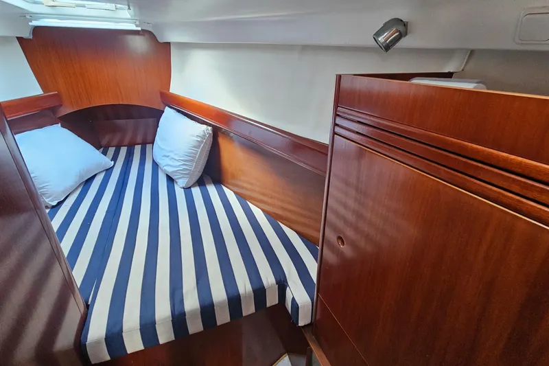 Slide: The Image of Cozy cabin interior of 2004 Beneteau First 36.7 with striped bedding and wooden finish. - 19