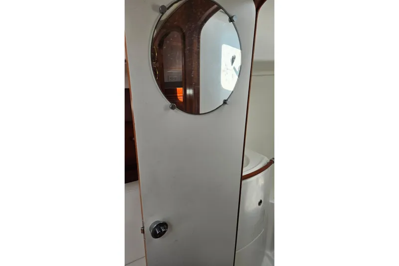 Slide: The Image of Interior of 2004 Beneteau First 36.7 sailboat, featuring a round mirror and wooden accents. - 22