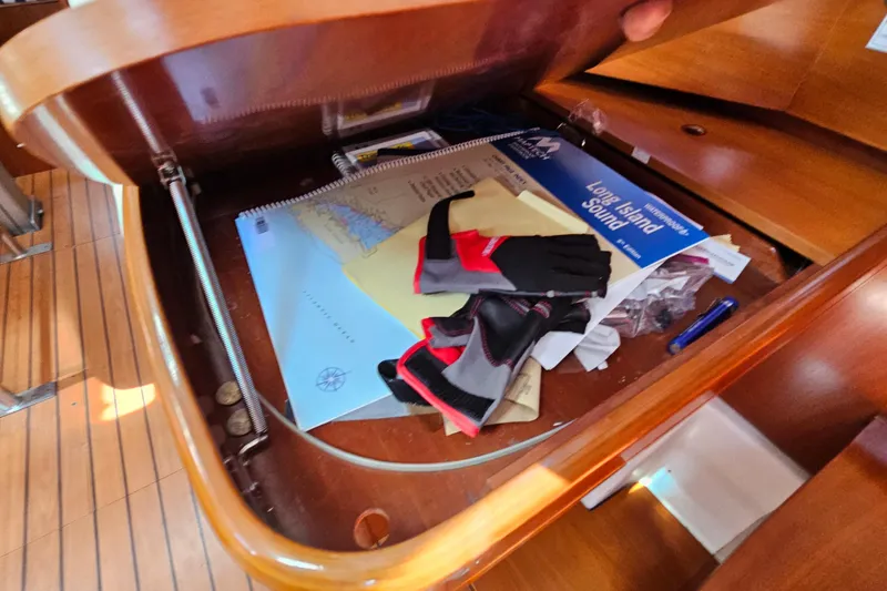 Slide: The Image of Storage compartment in 2004 Beneteau First 36.7 with maps, gloves, and sailing gear. - 23
