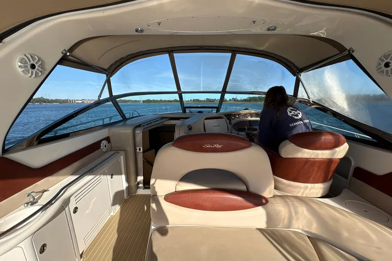 Slide: The Image of 1999 Sea Ray 380 Sundancer interior with person at helm, overlooking calm waters. - 11