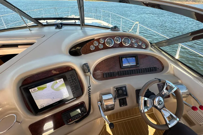 Slide: The Image of 1999 Sea Ray 380 Sundancer helm with navigation equipment and steering wheel on open water. - 12
