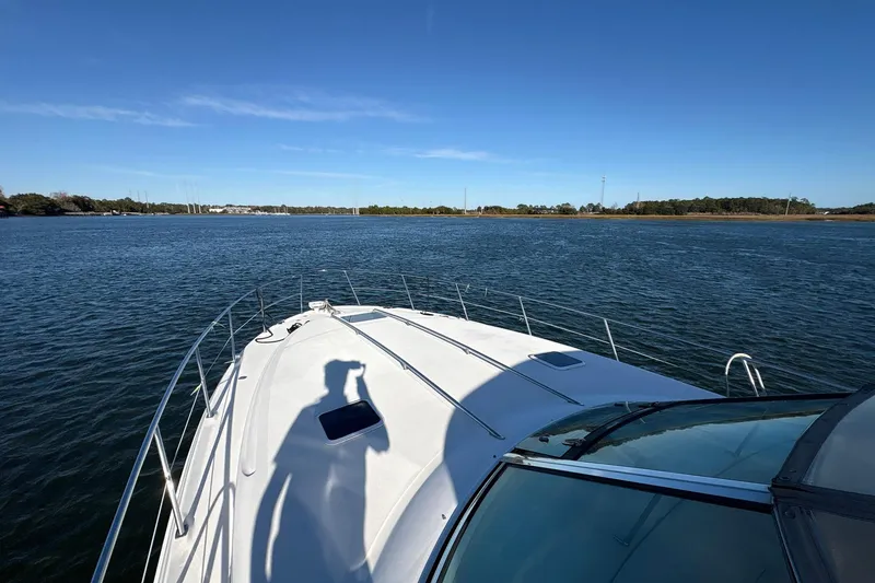 Slide: The Image of 1999 Sea Ray 380 Sundancer cruising on a calm lake under a clear blue sky. - 14