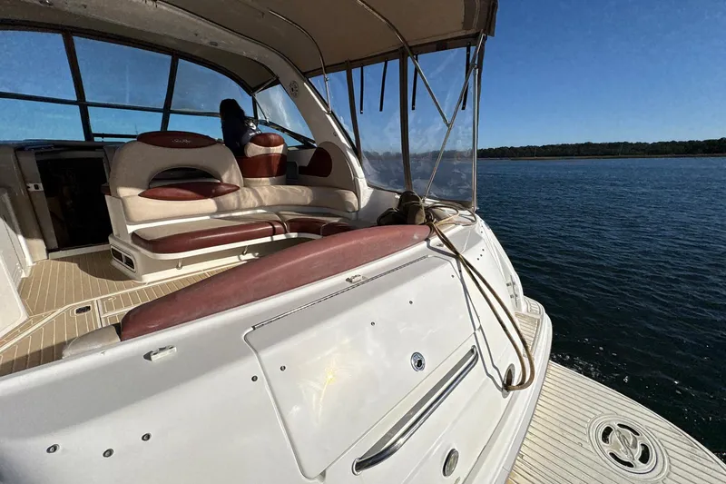 Slide: The Image of 1999 Sea Ray 380 Sundancer boat interior with seating, on a calm water body. - 7