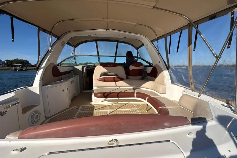 Slide: The Image of 1999 Sea Ray 380 Sundancer boat interior with seating and helm, on calm water. - 8