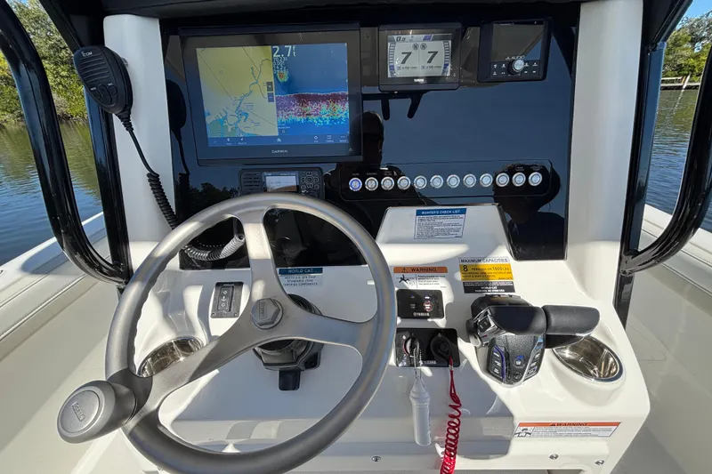 Slide: The Image of 2026 World Cat 235 TE boat dashboard with steering wheel, navigation screens, and controls. - 11
