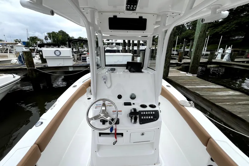 Slide: The Image of 2025 NauticStar 242L Offshore boat at marina, featuring helm controls and seating. - 4