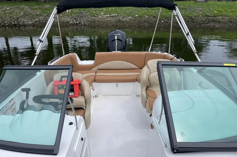 Slide: The Image of 2025 NauticStar 223 DC Deck boat interior with tan seating and black canopy. - 2