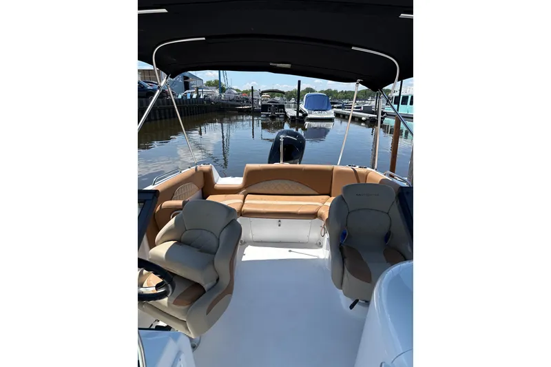 Slide: The Image of 2025 NauticStar 223 DC Deck boat interior with seating, docked at marina. - 2