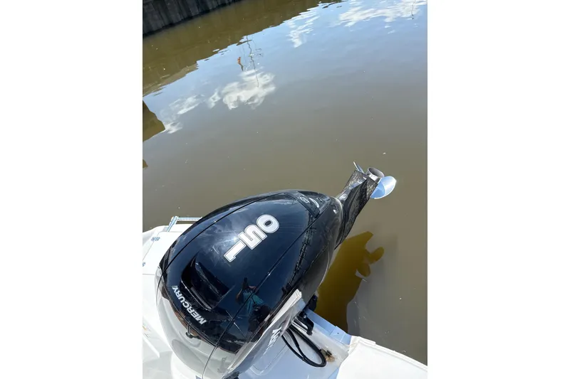 Slide: The Image of 2025 NauticStar 223 DC Deck boat with Mercury outboard motor on calm water. - 8