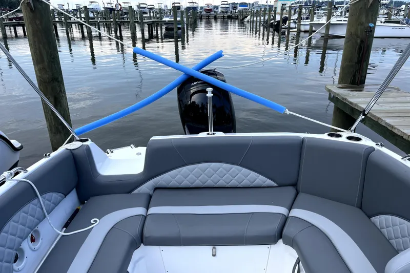 Slide: The Image of 2025 NauticStar 223 DC boat interior with gray seating, docked at marina. - 5