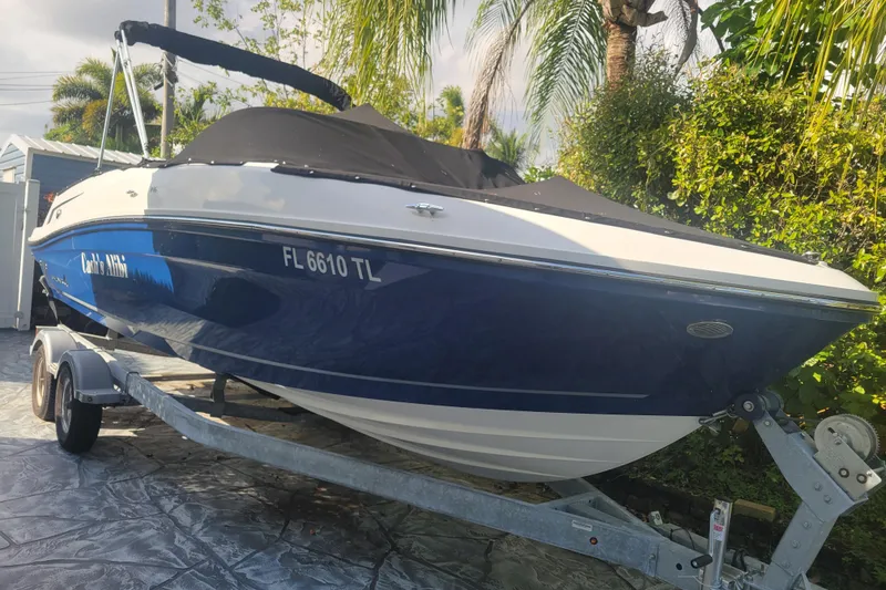 The Image of 2023 Bayliner VR6 Bowrider OB on trailer, parked outdoors with lush greenery. - 1