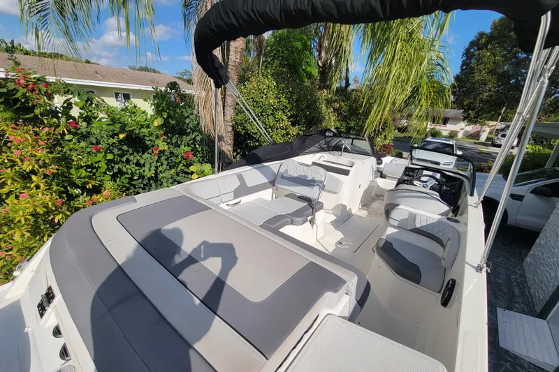 Slide: The Image of 2023 Bayliner VR6 Bowrider OB boat interior with seating, surrounded by lush greenery. - 13