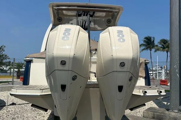 Slide: The Image of 2022 Scout 277 Dorado boat with dual outboard engines, docked under clear blue sky. - 6