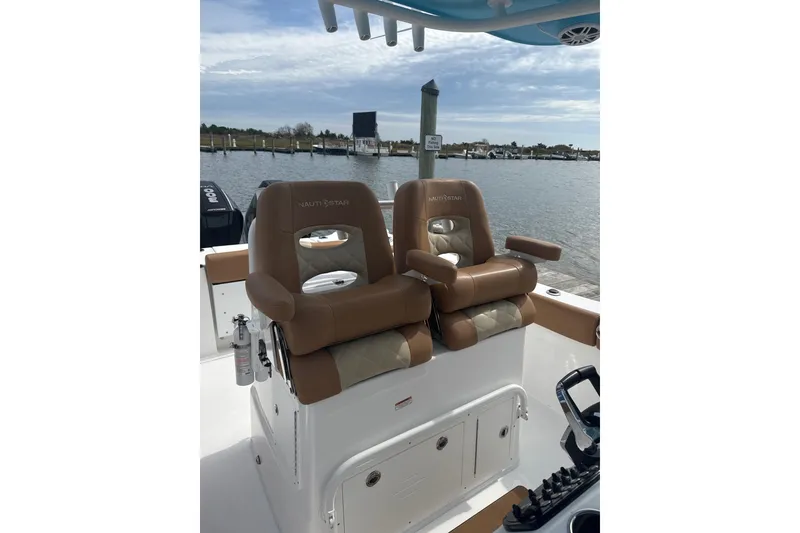 Slide: The Image of 2025 NauticStar 292 Legacy boat seats with armrests, docked by the water. - 6