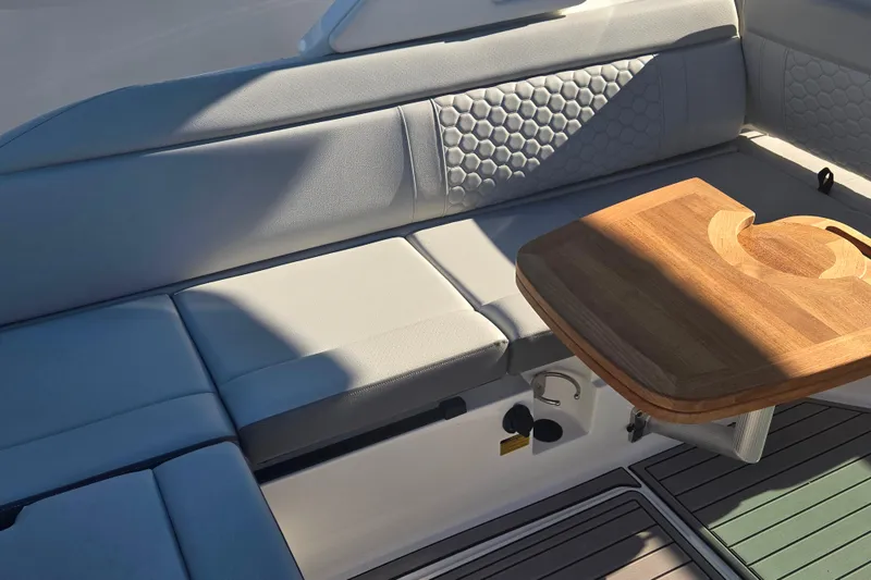 Slide: The Image of 2024 Sea Ray SDX 250 Outboard interior with cushioned seating and wooden table. - 23