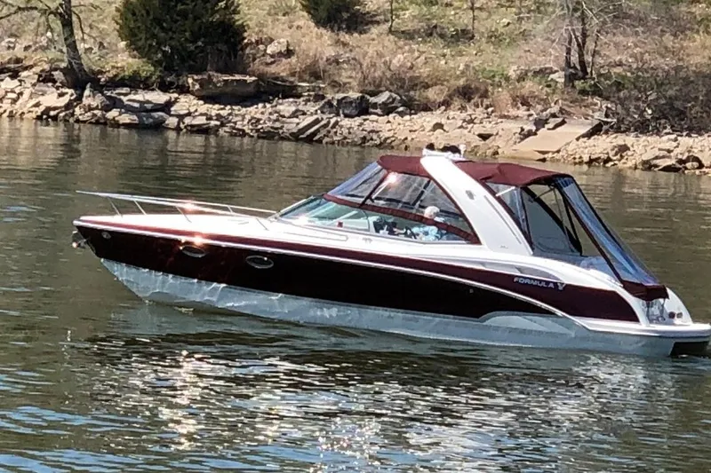 Slide: The Image of 2007 Formula 310 Sun Sport boat cruising on a calm lake near a rocky shoreline. - 1