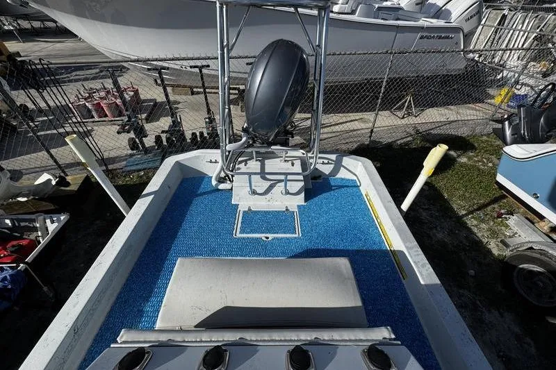 Slide: The Image of 2001 Gulf Coast 200 boat interior with blue flooring and motor, docked near other boats. - 19