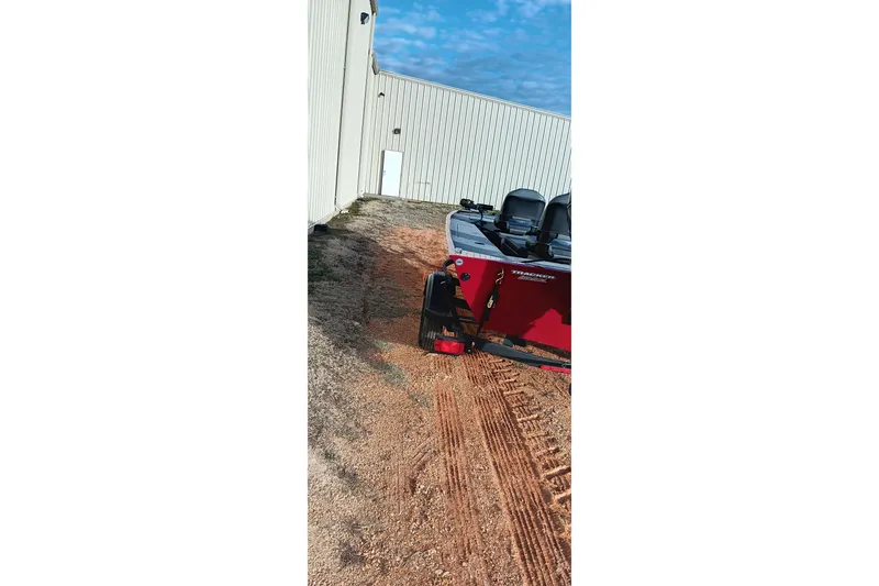 Slide: The Image of 2026 Tracker Panfish 17 boat parked on dirt near a building. - 13