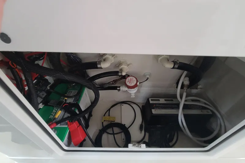 Slide: The Image of Electrical and plumbing components inside a 2025 Ranger 2360 Bay boat compartment. - 25