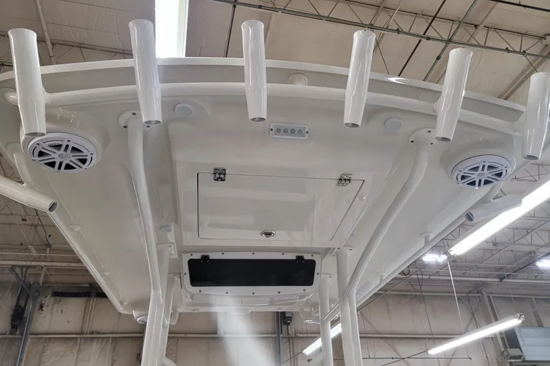 Slide: The Image of 2025 Ranger 2360 Bay boat's T-top with rod holders and speakers in a warehouse. - 27
