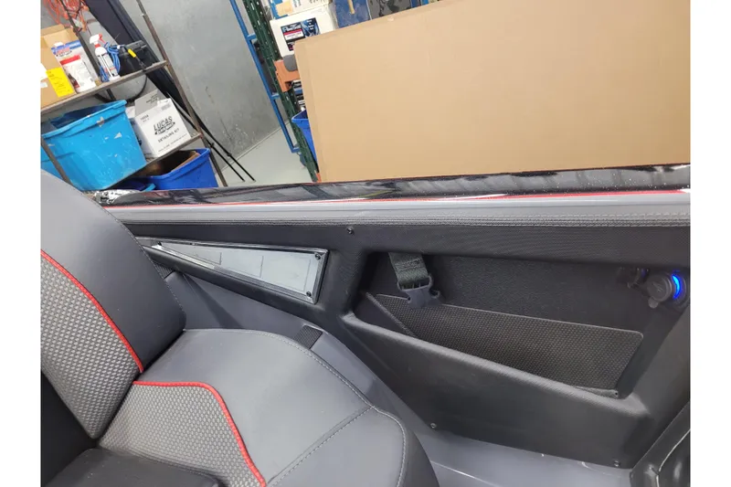 Slide: The Image of 2023 Ranger Z521R interior with black and red seat, storage compartment, and blue LED light. - 21