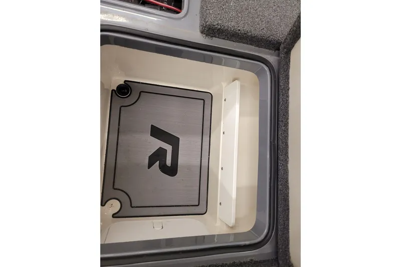Slide: The Image of 2023 Ranger Z521R boat storage compartment with logo, featuring carpeted edges. - 6