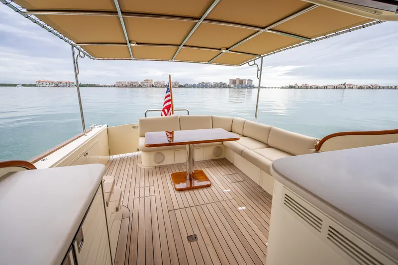 Slide: The Image of 2020 Palm Beach Motor Yachts PB50 deck with seating, table, and scenic waterfront view. - 10
