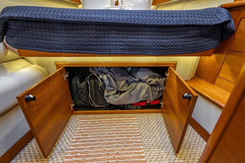 Slide: The Image of Under-bed storage in 2020 Palm Beach Motor Yachts PB50, featuring wooden cabinets and cozy bedding. - 35