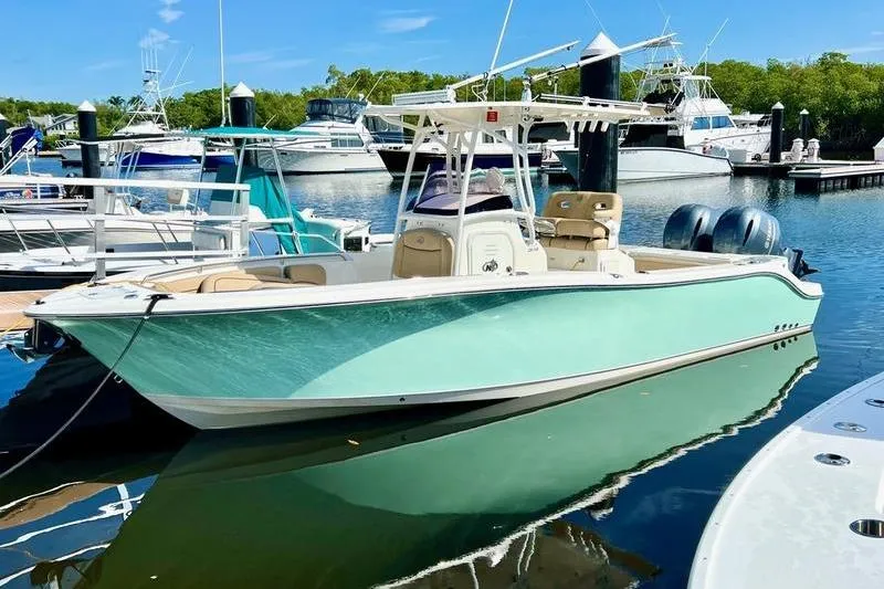 The Image of 2019 NauticStar 25 XS boat docked in a marina, surrounded by other vessels. - 1