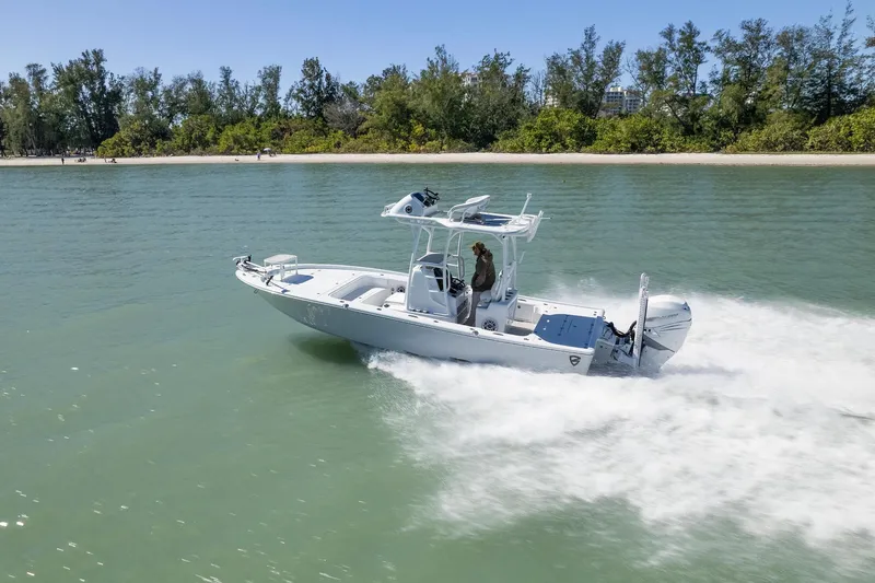 Slide: The Image of 2026 Barker Boatworks 26 Calibogue Bay on water at sunset, city skyline in background. - 2