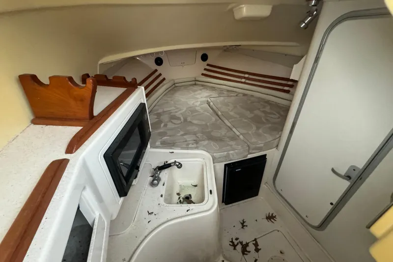 Slide: The Image of 2005 Grady-White Express 265 cabin interior with bed, sink, and storage. - 17