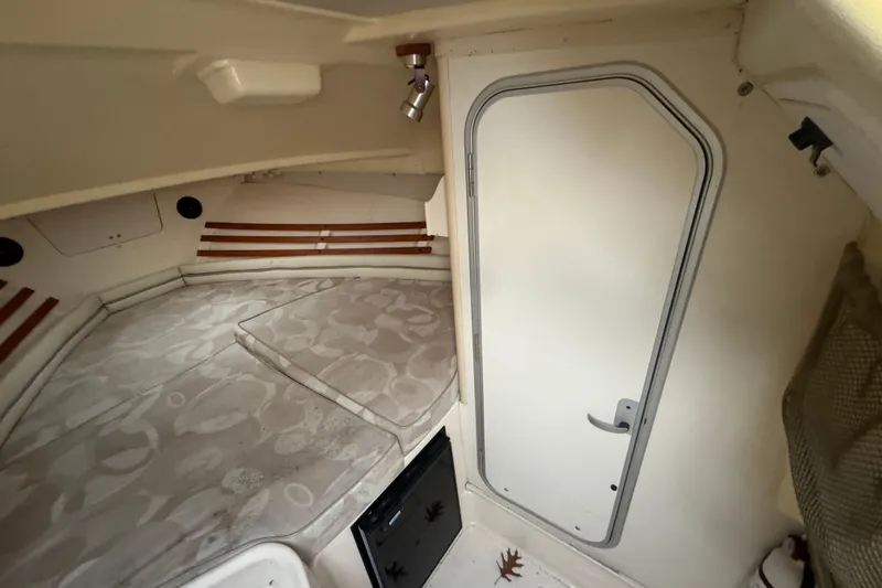 Slide: The Image of 2005 Grady-White Express 265 cabin interior with bed and door, showcasing cozy design. - 18