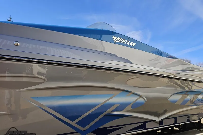 Slide: The Image of 2007 Hustler 41 Razor boat with sleek design and blue accents under clear sky. - 20