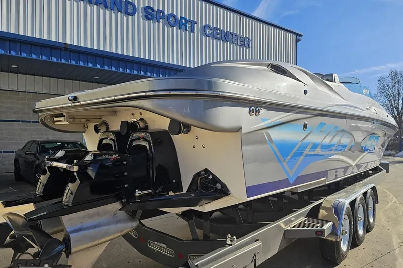 Slide: The Image of 2007 Hustler 41 Razor boat on trailer outside a sports center. - 32