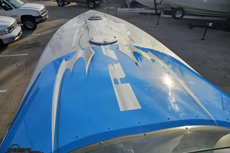 Slide: The Image of 2007 Hustler 41 Razor boat with blue and white design, parked near other vehicles. - 70