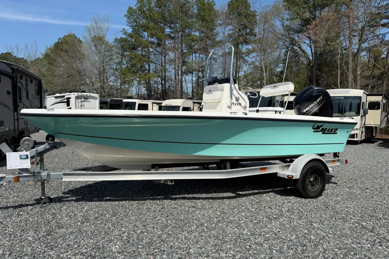 The Image of 2018 Mako 19 CPX boat on trailer, parked outdoors with trees in background. - 15