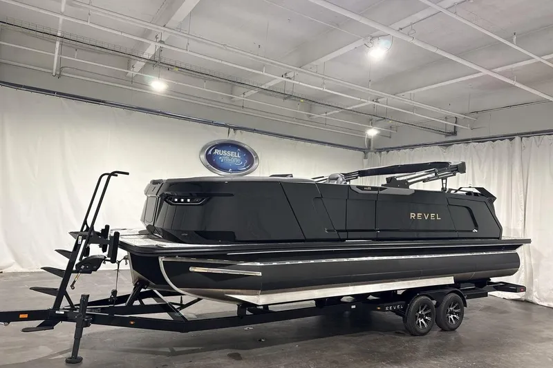 Slide: The Image of 2026 Revel RS25 boat in showroom, sleek black design on trailer. - 0