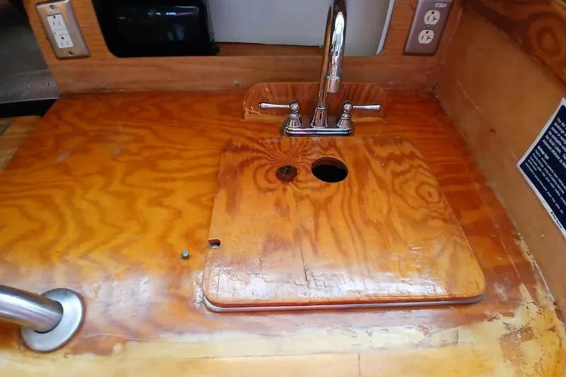 Slide: The Image of 1976 Islander Freeport boat interior with wooden sink cover and faucet. - 13