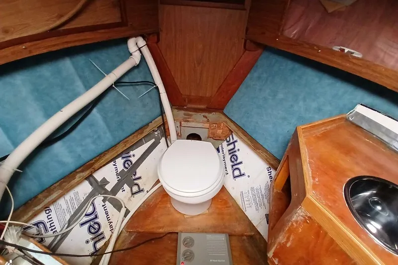 Slide: The Image of 1976 Islander Freeport boat interior with toilet and sink, featuring wood and blue paneling. - 18