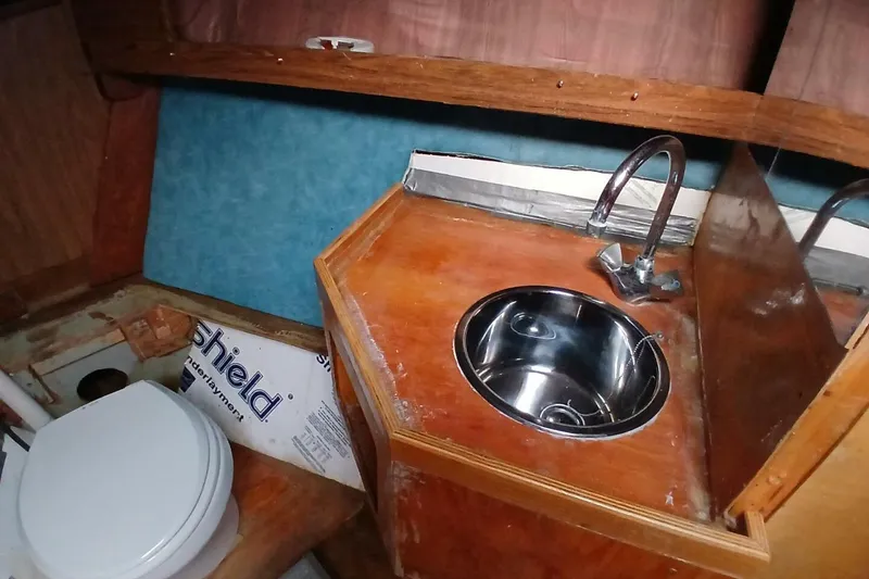 Slide: The Image of 1976 Islander Freeport boat interior with sink and toilet in wooden cabin. - 19
