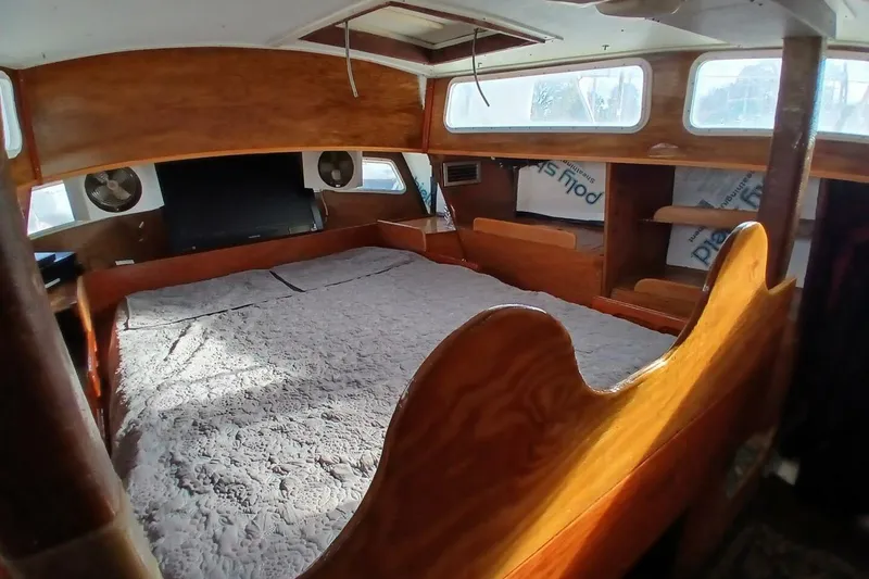Slide: The Image of Interior of a 1976 Islander Freeport sailboat with wooden furnishings and a cozy bed. - 26