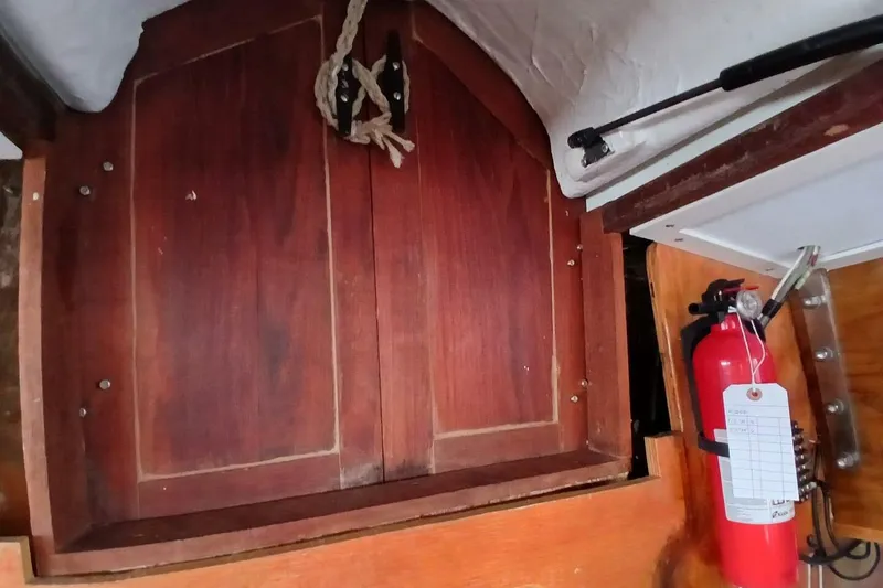 Slide: The Image of Wooden cabinet and fire extinguisher inside 1976 Islander Freeport boat cabin. - 31