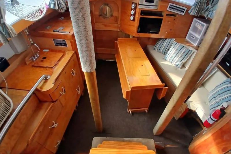 Slide: The Image of 1976 Islander Freeport yacht interior with wooden cabinetry, dining table, and cozy seating area. - 5