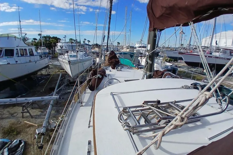 Slide: The Image of 1976 Islander Freeport sailboat on land, surrounded by other boats, under a clear blue sky. - 51