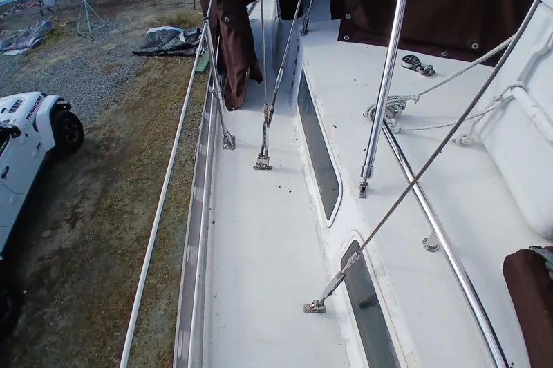 Slide: The Image of 1976 Islander Freeport sailboat deck with rigging, parked beside a white vehicle. - 56