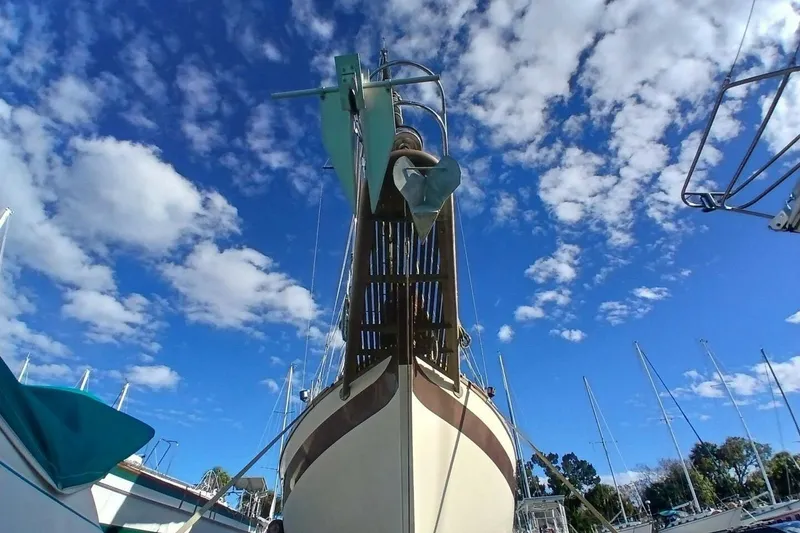 Slide: The Image of 1976 Islander Freeport sailboat under a vibrant blue sky with scattered clouds. - 62