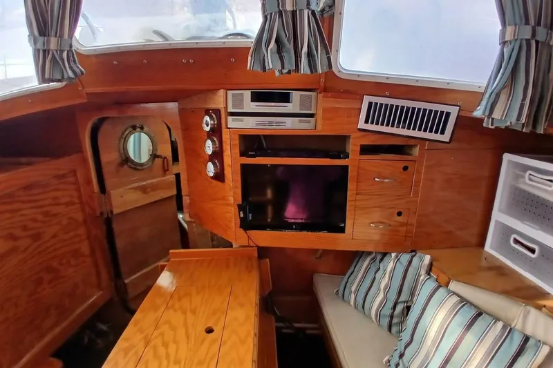 Slide: The Image of 1976 Islander Freeport yacht interior with wood paneling, striped cushions, and nautical decor. - 9
