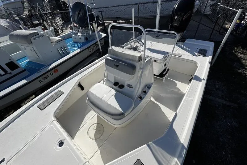 Slide: The Image of 2022 Mako 18 LTS boat interior with seating and console, docked outdoors. - 13