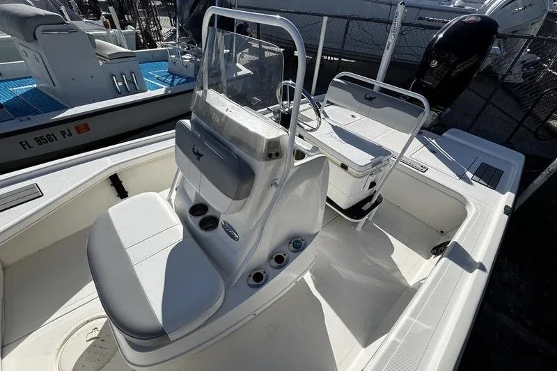 Slide: The Image of 2022 Mako 18 LTS boat interior with seating and console, docked in marina. - 16