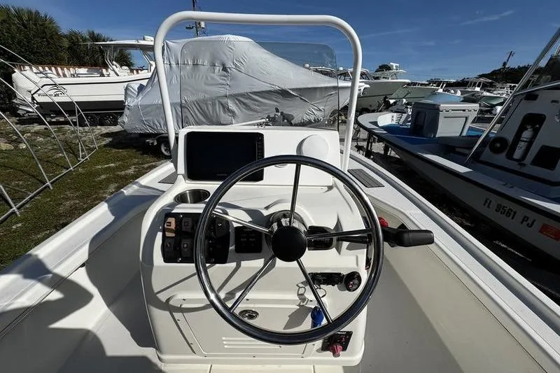 Slide: The Image of 2022 Mako 18 LTS boat console with steering wheel and controls in a marina setting. - 19